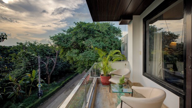A balcony with a potted plant, a chair, and a glass table. - BlueNeck Sec 40 Unitech Cyber Park Gurugram (Gurugram)