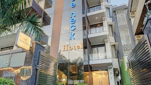 A hotel entrance with a modern facade, a visible balcony, and potted plants. - BlueNeck Sec 40 Unitech Cyber Park Gurugram (Gurugram)