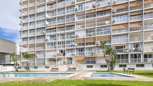 Un hotel de varios pisos con balcones, piscina y un pequeño jardín.