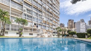 Un edificio residencial alto con piscina al frente.