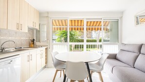 Una cocina moderna con comedor, ventanas amplias y un sofá gris.