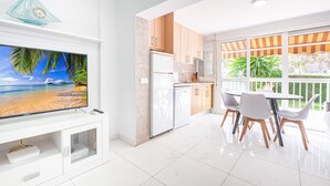 Una cocina moderna con armarios blancos, un refrigerador y un comedor con sillas y una mesa blancos.