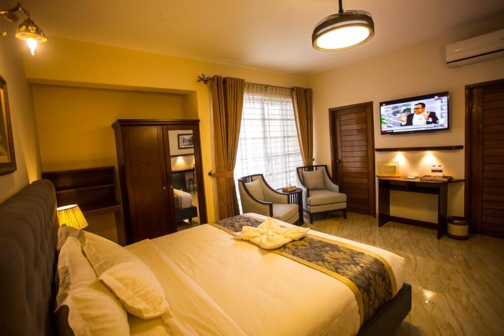 Una habitación de hotel con cama, escritorio, silla, televisor y armario.