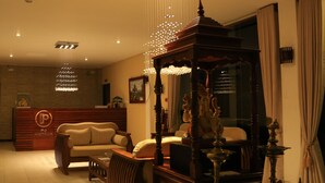 A reception area with a reception desk, a sofa, a coffee table, and a decorative fountain. - PJ Hotels Jaffna (Valikamam East)