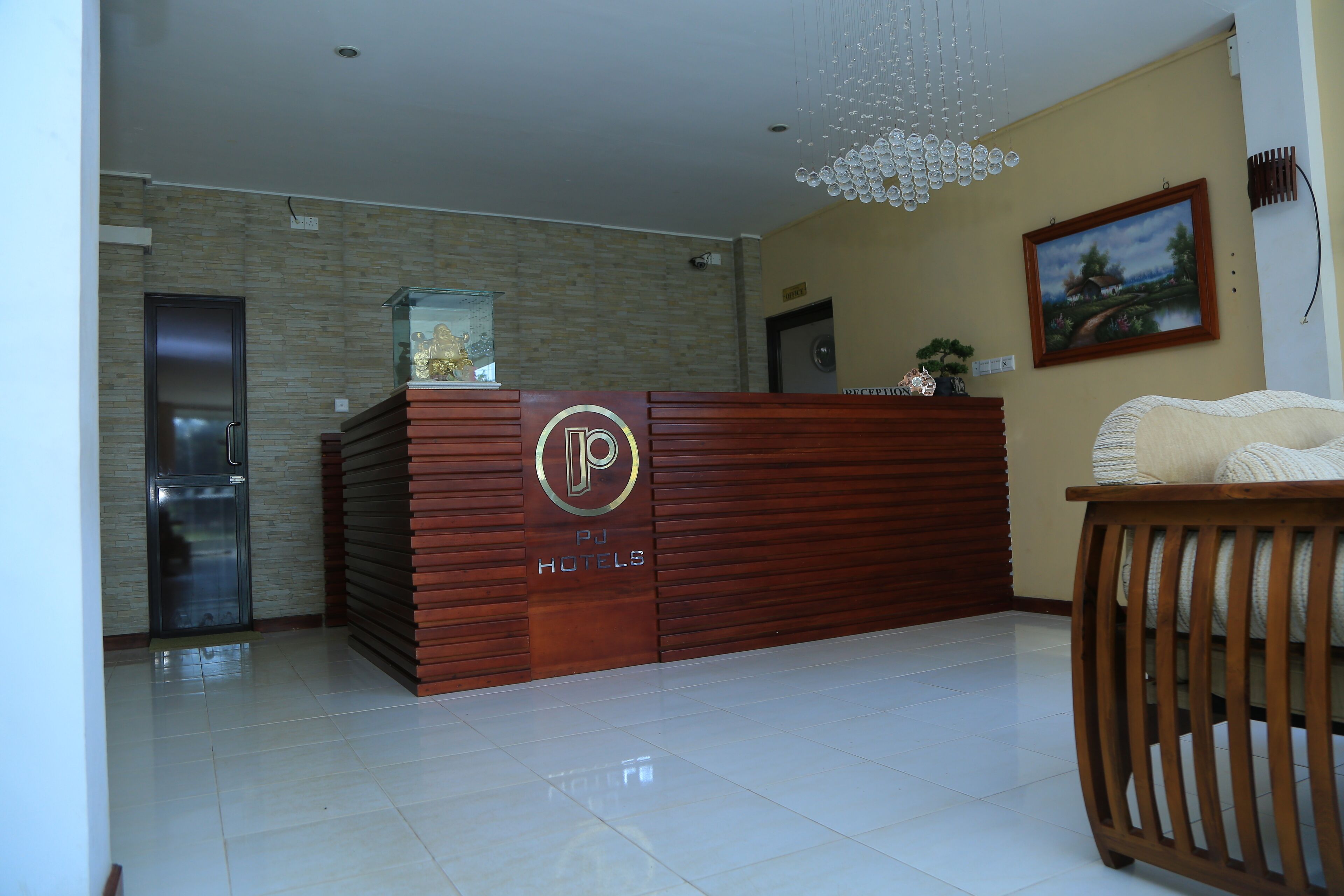 A reception desk with a logo, a refrigerator, a wooden bench, and a painting on the wall.