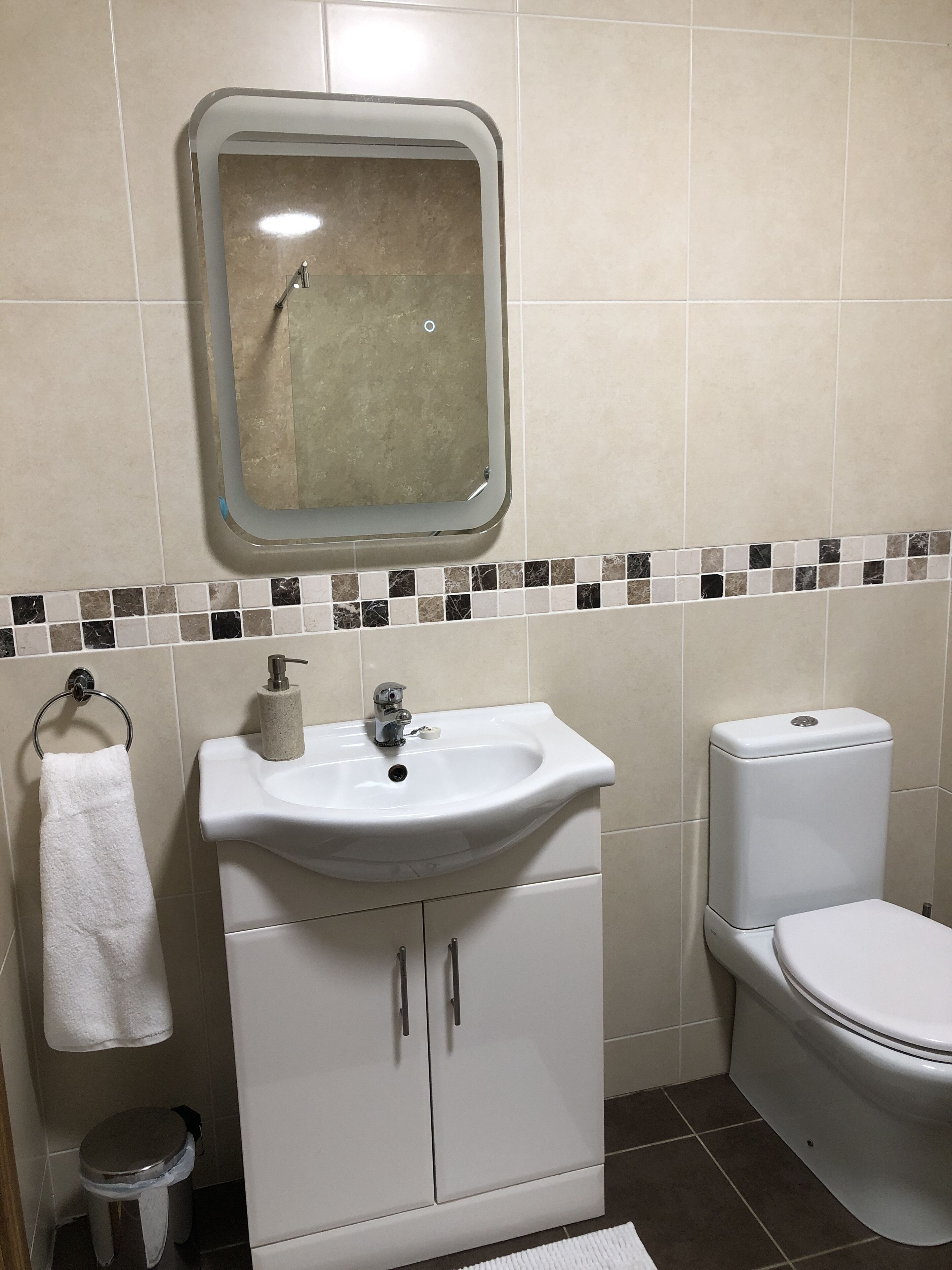 Une salle de bain avec un lavabo blanc, des toilettes et un miroir au-dessus du lavabo.