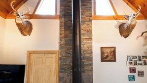 Una habitación acogedora con estufa de leña, techo de madera y pared de piedra.