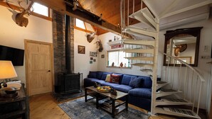 Una sala de estar acogedora con un sofá azul, una mesa de centro de madera y una escalera de caracol.