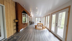 Un pasillo con paneles de madera, un banco de madera y ventanas grandes.
