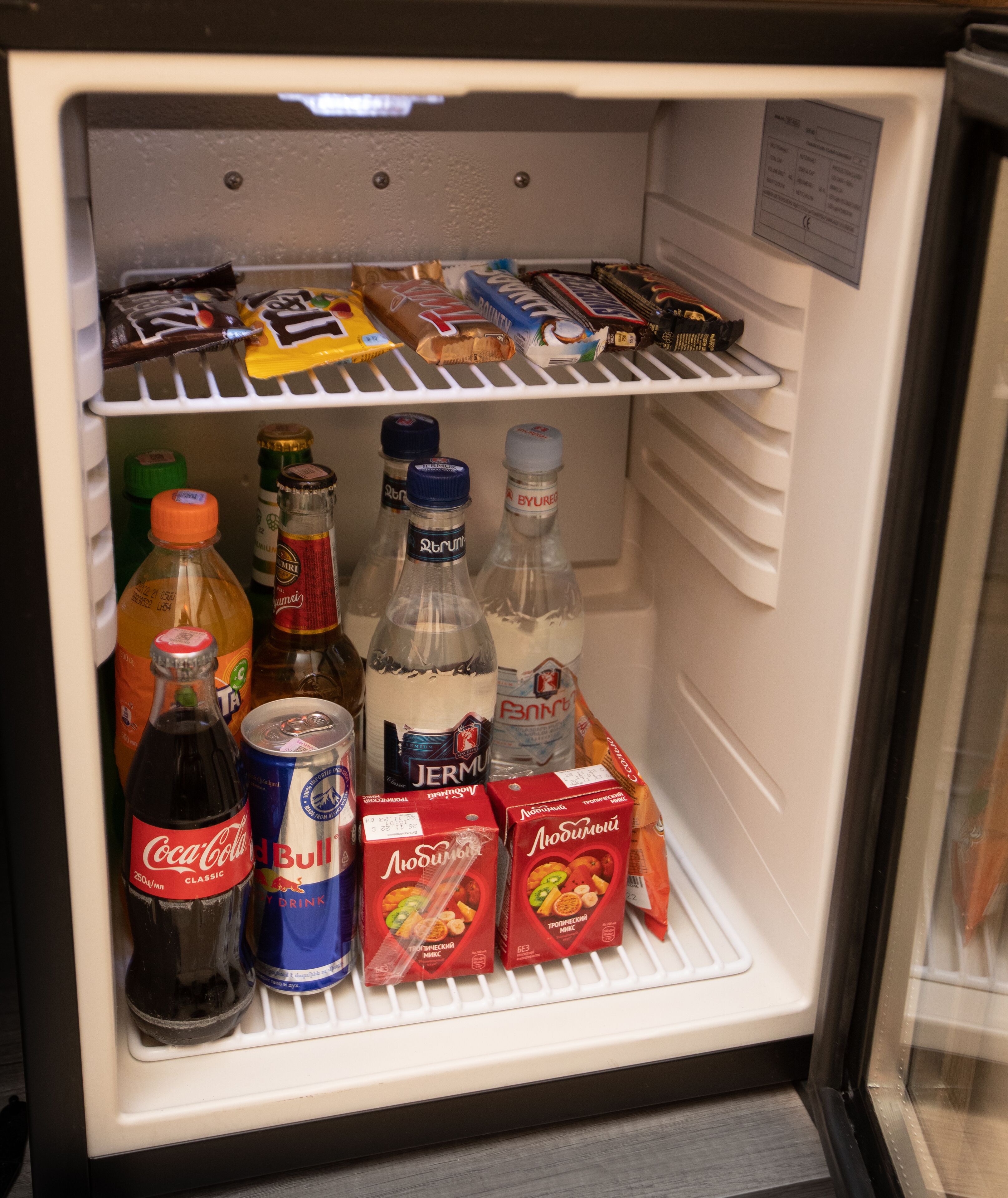 A refrigerator stocked with various beverages and snacks.