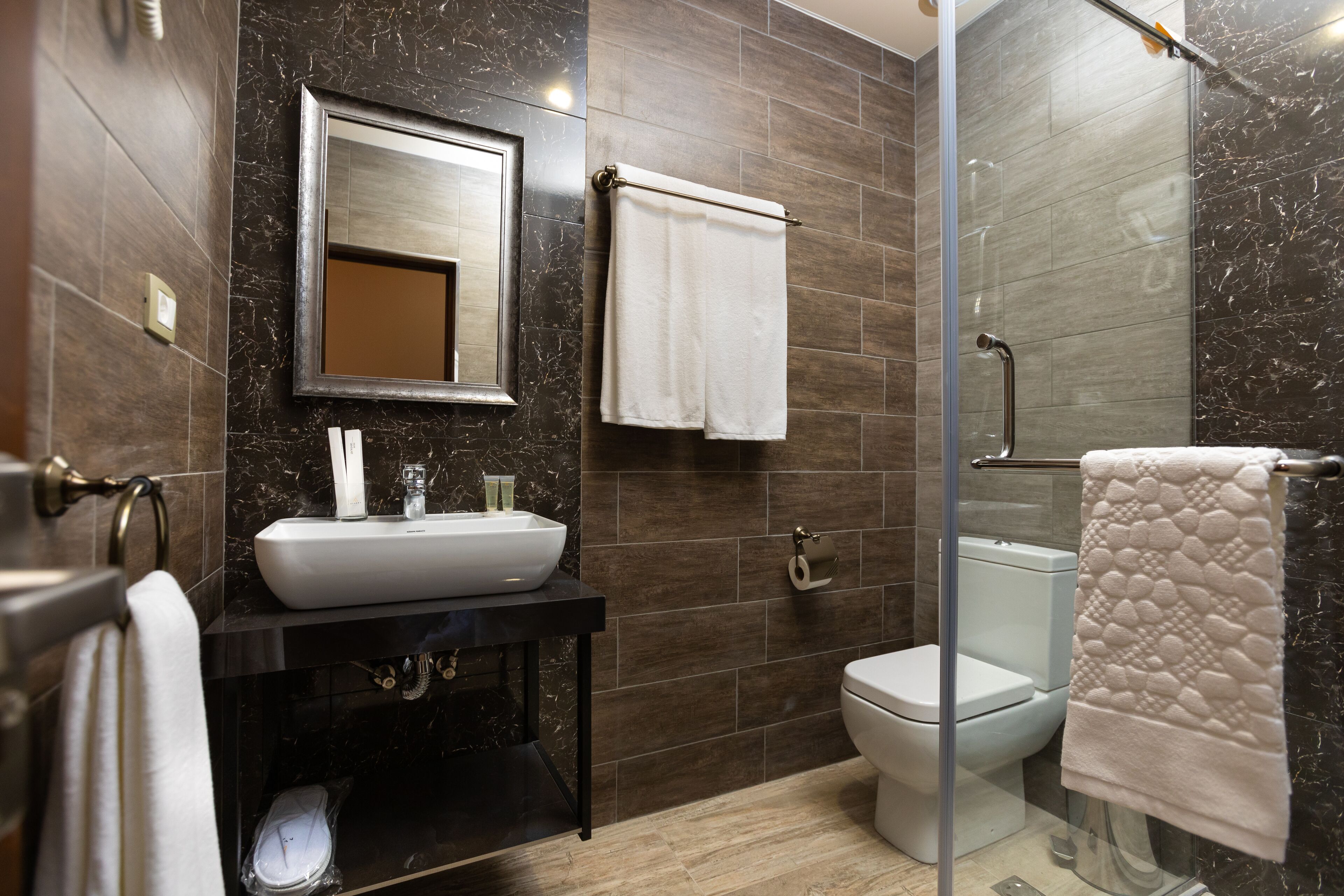 A modern bathroom with a large sink, mirror, toilet, and glass shower enclosure.