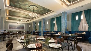 Un restaurante espacioso con suelo de mármol, varias mesas de comedor y asientos tapizados en azul.
