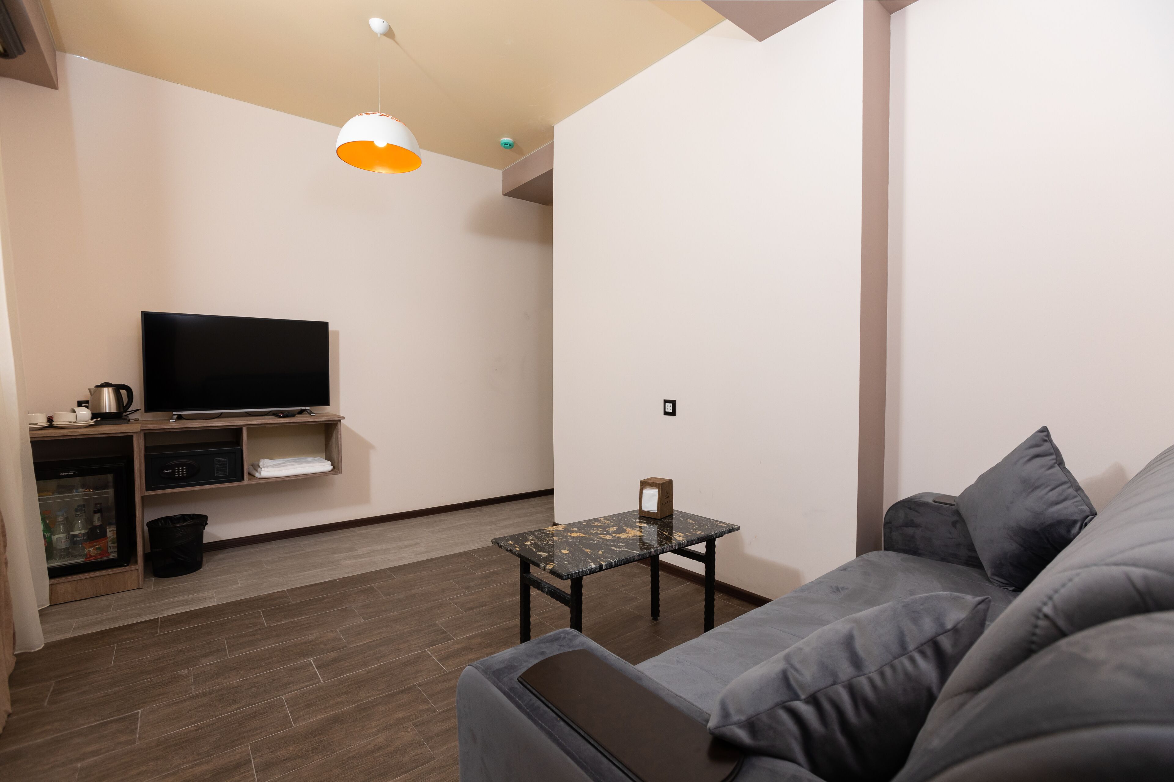 Ein modernes Wohnzimmer mit Fernseher, einem kleinen Tisch und einer Couch.