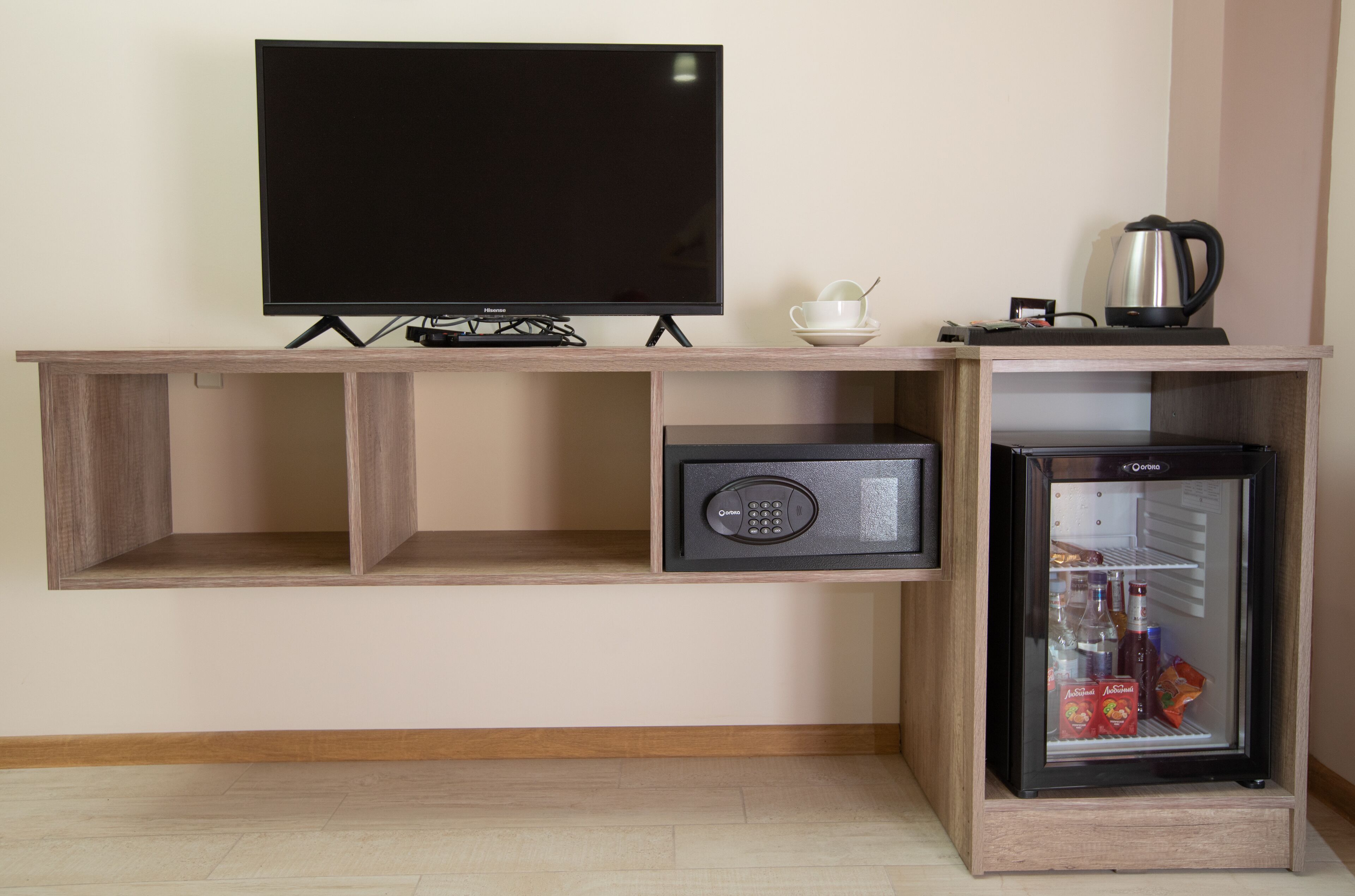 A compact living space with a flat-screen TV, a coffee maker, a mini-fridge, and a speaker.