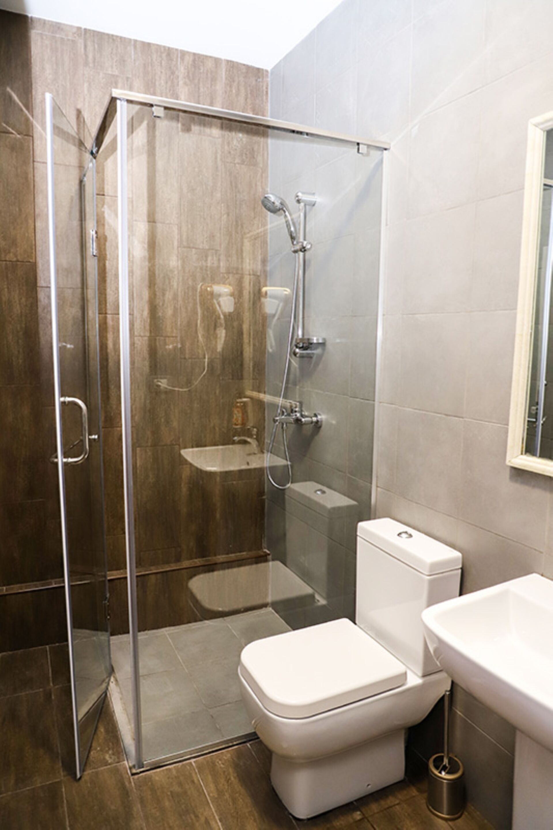 Un baño moderno con ducha de mampara de vidrio, inodoro y lavabo.