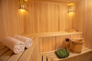 A wooden sauna with benches, a bench with towels, and a bucket of leaves. - Alaska Resort (Tsaghkadzor)