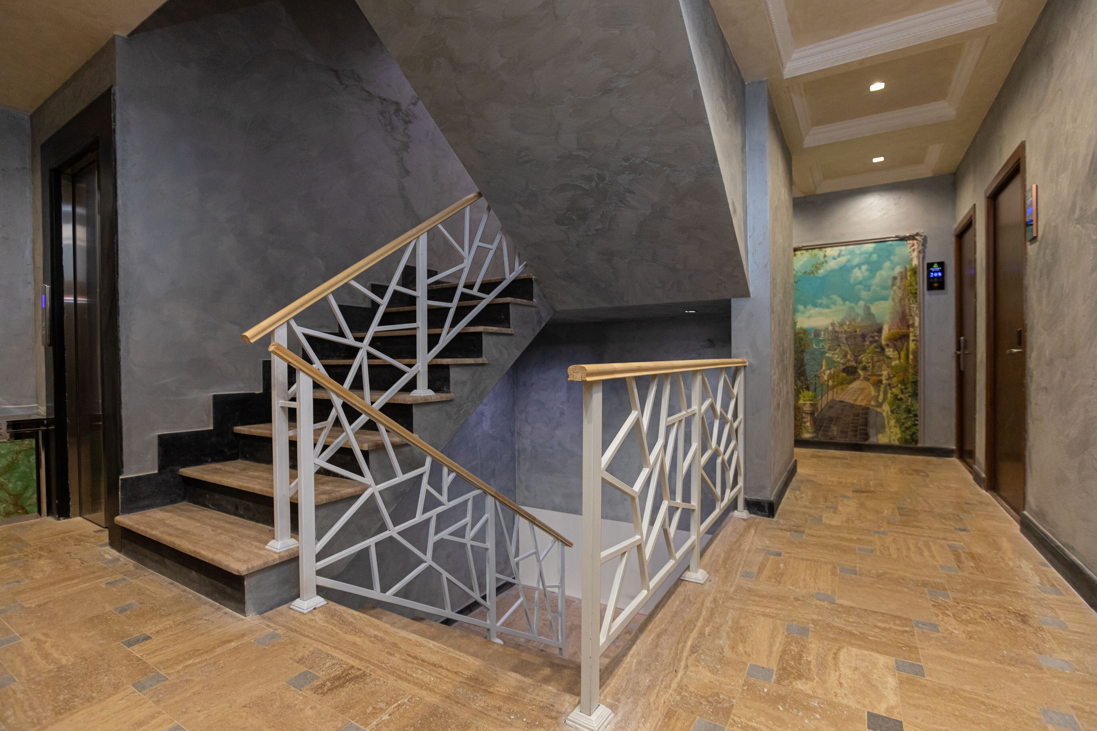 Un moderno vestíbulo de hotel con una escalera de madera, un mural en la pared y un mostrador de recepción.