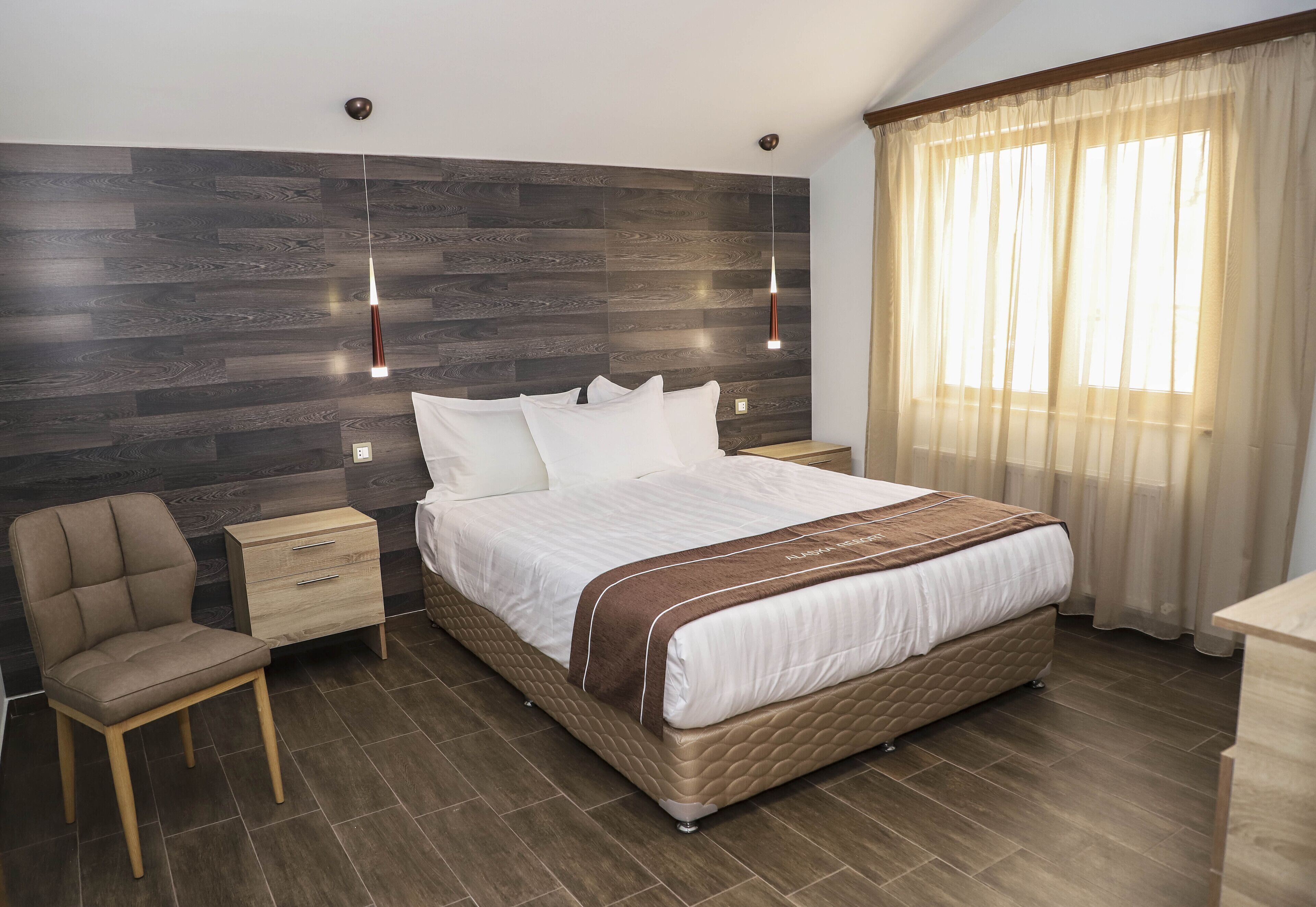 Ein Schlafzimmer mit einem großen Bett, einem Nachttisch, einem Sessel und einem Kleiderschrank.