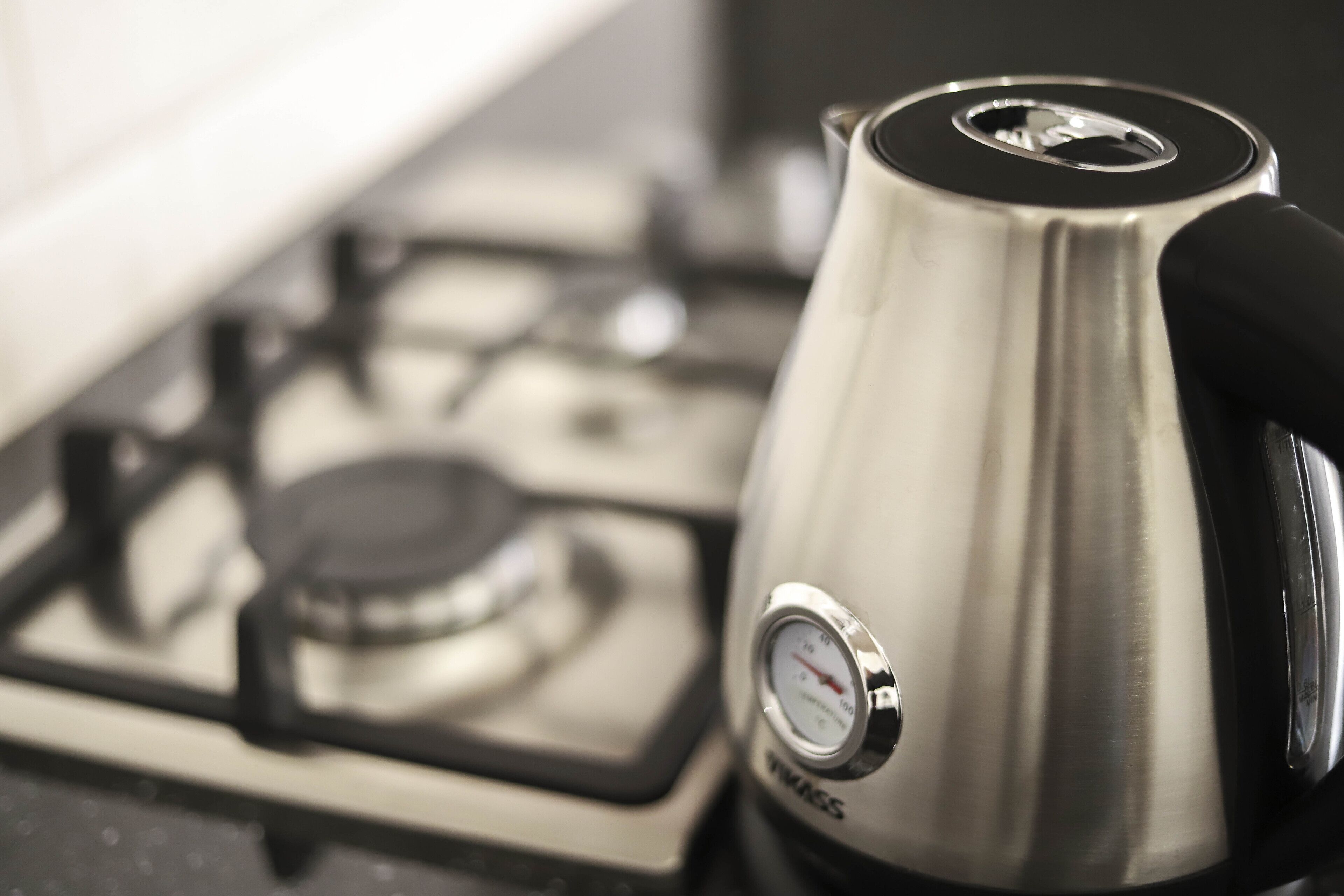A stainless steel kettle on a stove with a pressure gauge.