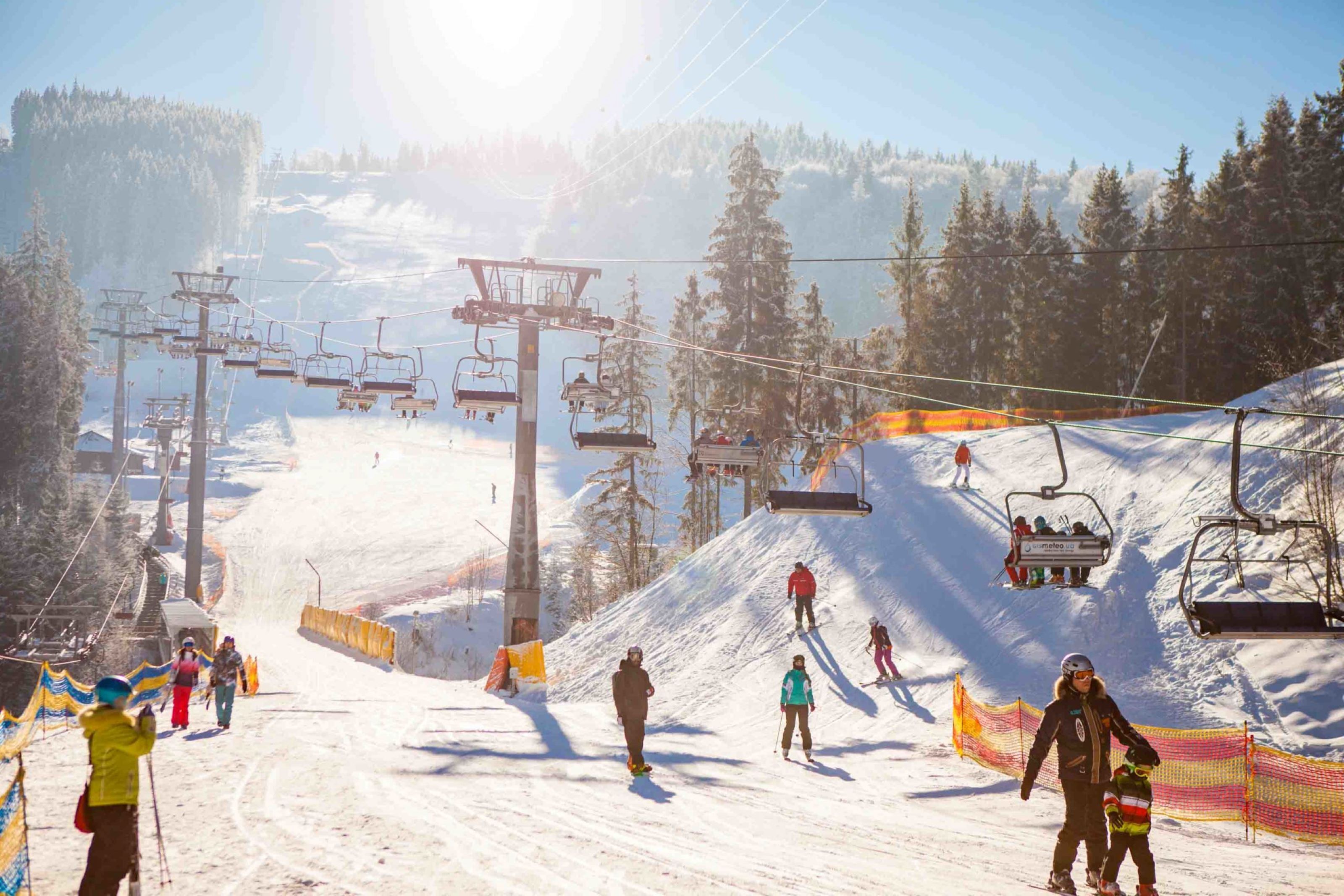 Une piste de ski avec un télésiège, des arbres et des skieurs.