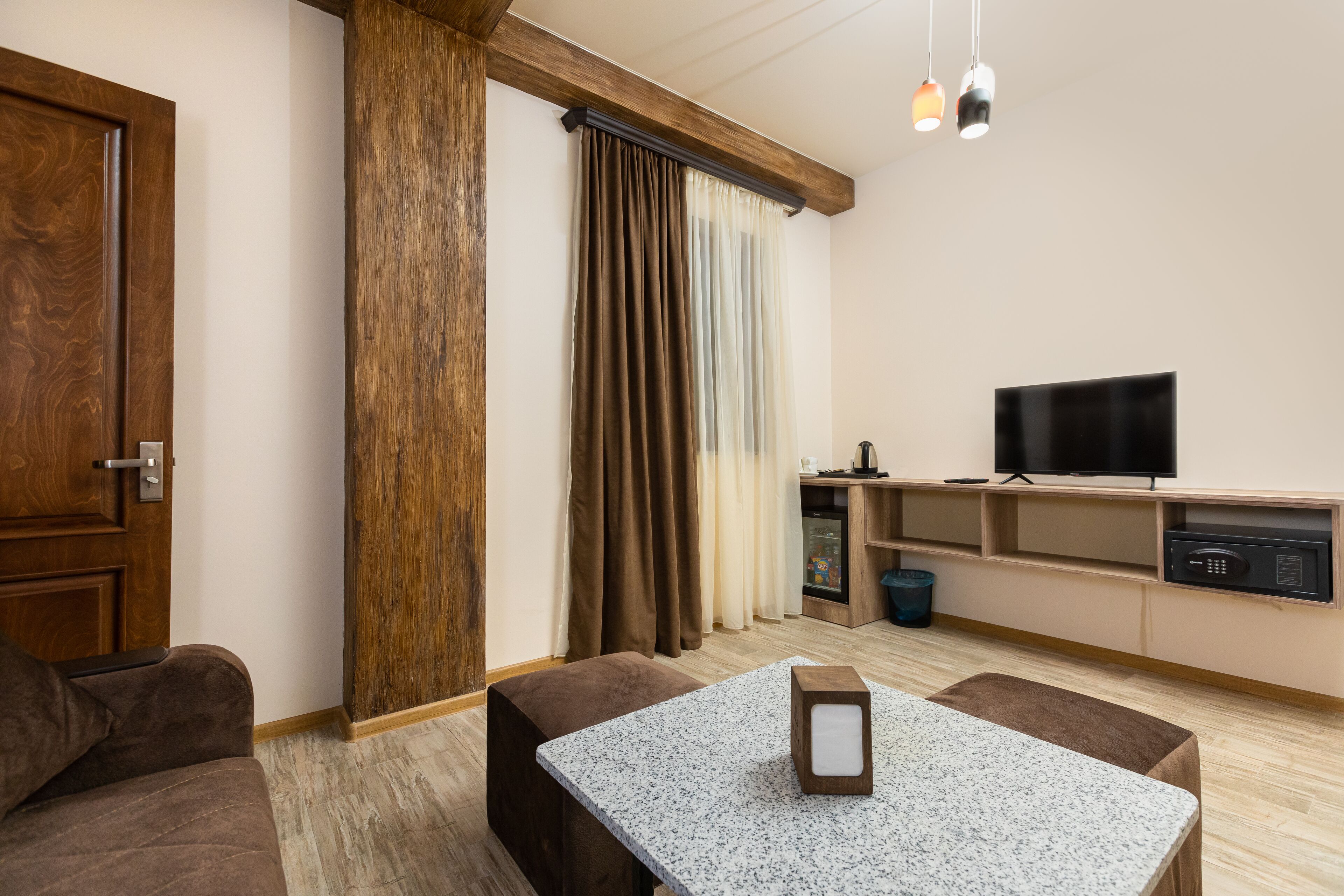 Sala de estar moderna com porta de madeira, uma TV sobre uma estante de madeira, uma mesa com uma caixa de luz e um sofá.