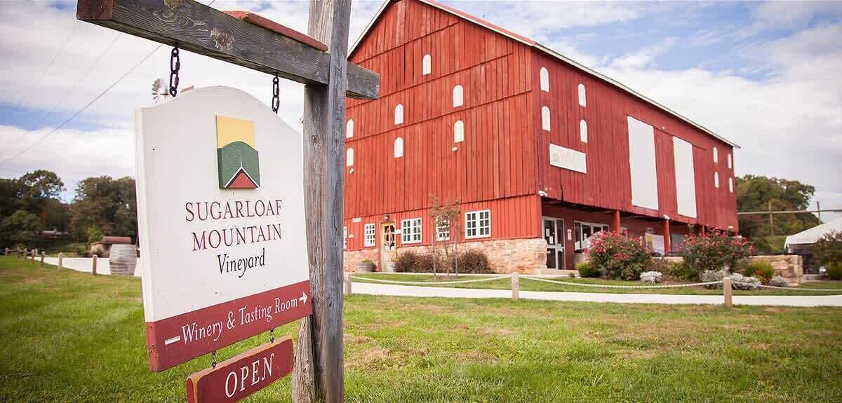 Una cascina rossa con un cartello per Sugarloaf Mountain Vineyard.