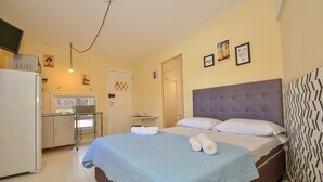 Een hotelkamer met een bed, een bureau, een koelkast en een deur.