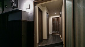 Un pasillo estrecho y tenuemente iluminado, con puertas de madera y suelo oscuro.