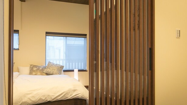 Un dormitorio con cama, almohadas, una ventana y un panel de madera.