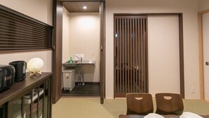 Una habitación compacta con zona de comedor, kitchenette y puerta corrediza que da al baño.