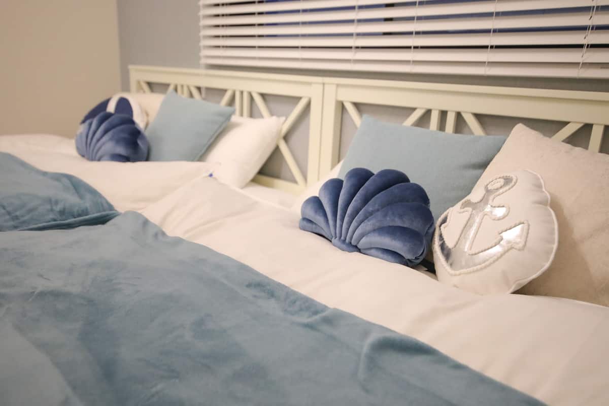 A bed with a white headboard, blue and white pillows, and a blue blanket.