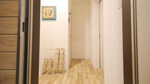 Un pasillo con suelo de madera, un zapatero y un cuadro en la pared.