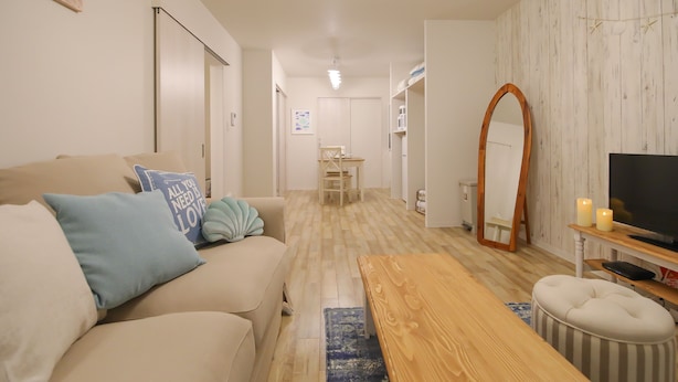 Una sala de estar con un sofá, una mesa de centro de madera, un televisor y un espejo.