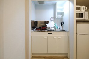A compact kitchen with a microwave, a kettle, and a toaster on the countertop.