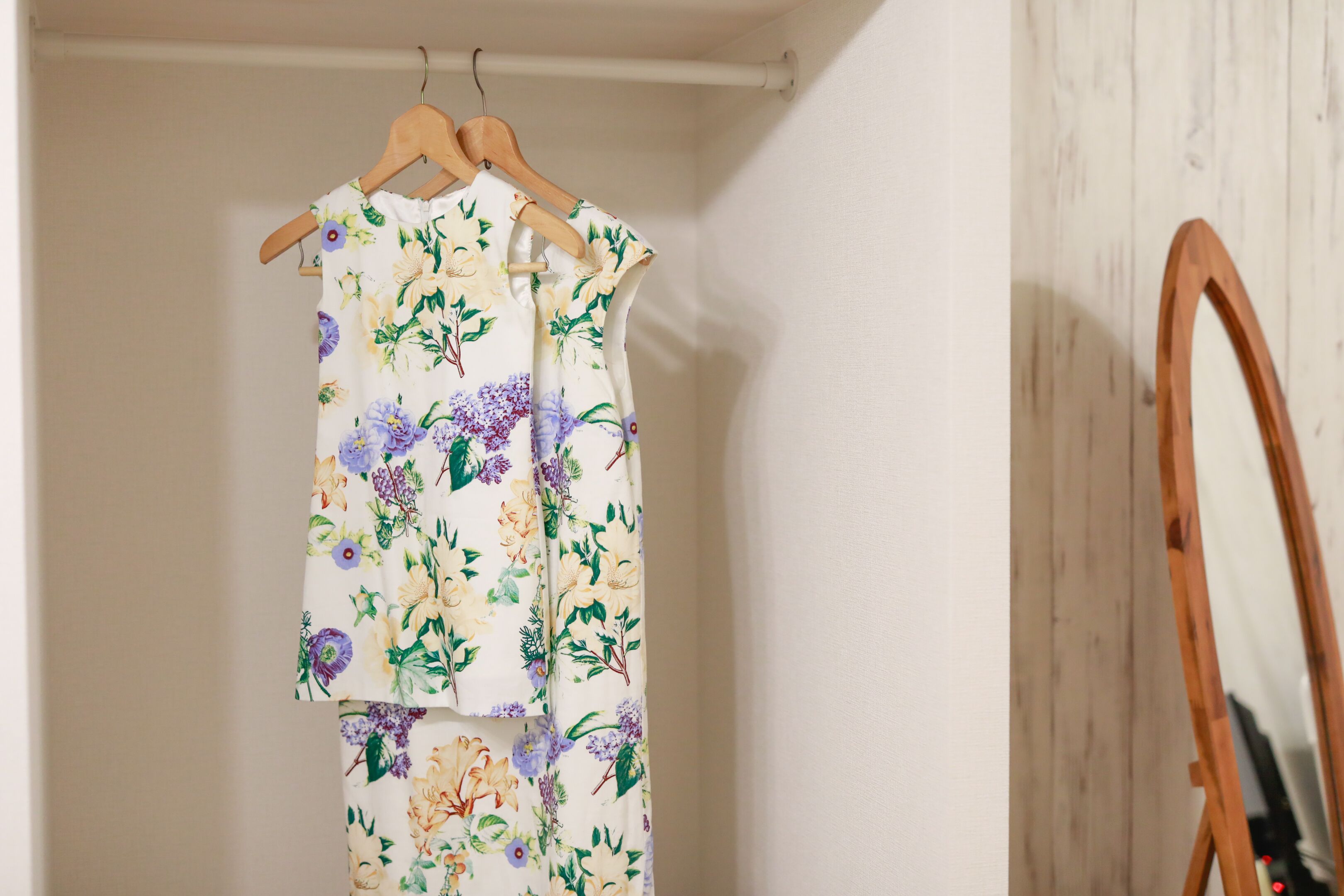 A room with a wooden easel and a floral-patterned garment hanging on a wooden hanger.