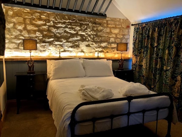 Relax in a serene bedroom with a stone headboard, plush bed, and stylish bedside lamps.