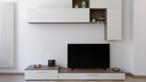 A modern living room with a flat-screen TV, built-in shelves, and a minimalist design. - Large Three-room Apartment in a Strategic Position (Desenzano del Garda)