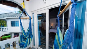 En balkon med blå og grønne hængekøjer, en hvid facade og udsigt til det indre.