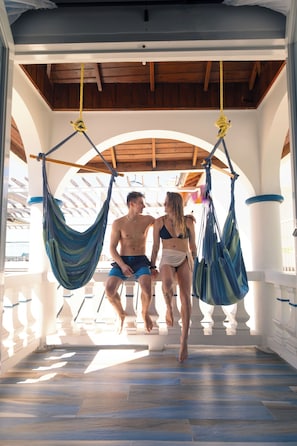 A couple walking through a covered outdoor area with hammocks and a wooden ceiling. - Blue Skies Beach Resort (Negril)