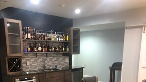 A modern kitchen with built-in appliances, a bar area with liquor bottles, and a dining area with a round table and chairs. - 12 minutes to PennState (Bellefonte)