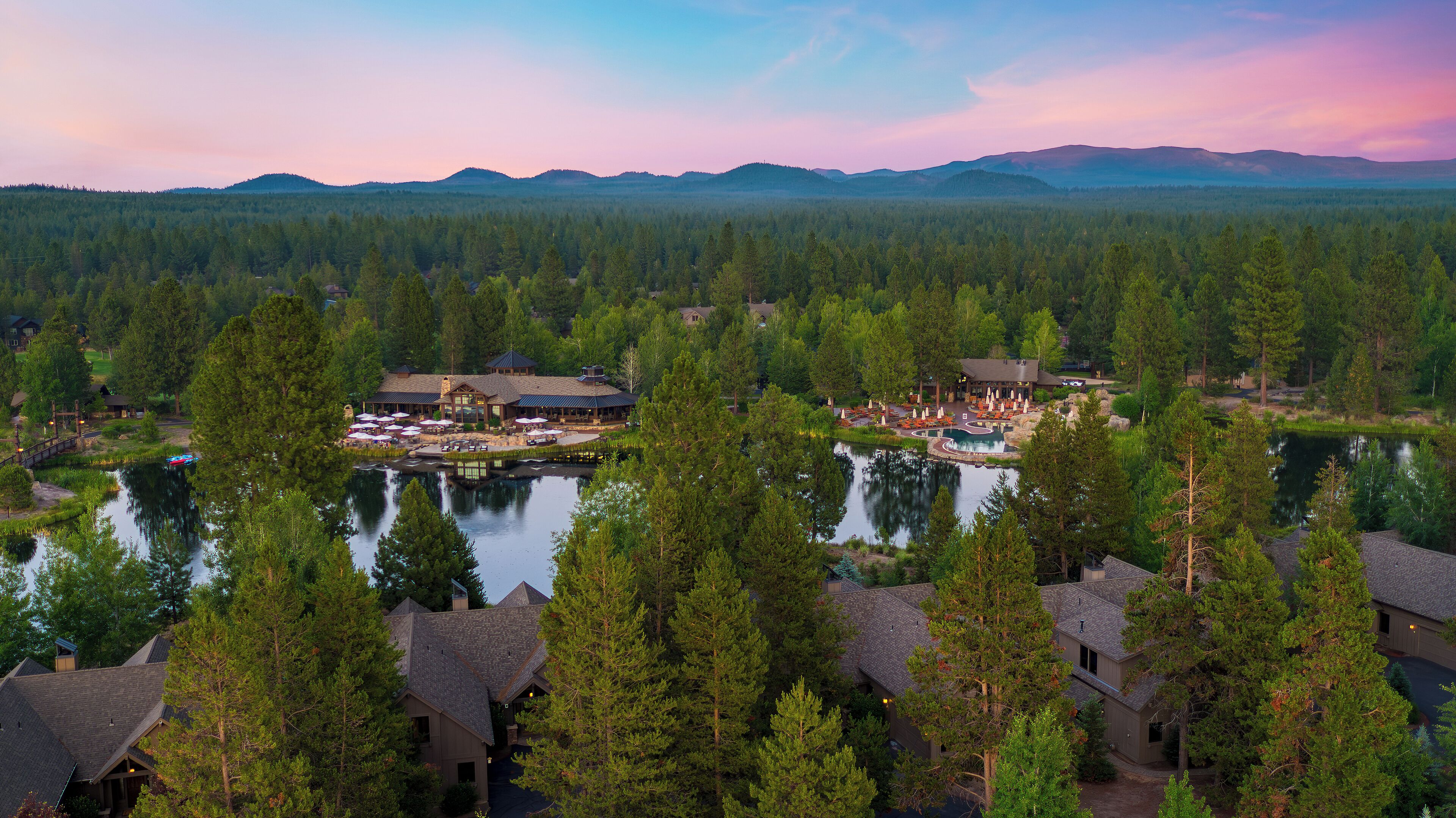 A lodge with multiple buildings, a lake, and surrounding forest.