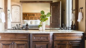 Une salle de bain avec des meubles en bois, un comptoir en marbre et une plante en pot.