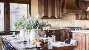 Une table à manger dressée avec des assiettes, des verres et un centre de table composé de verdure.