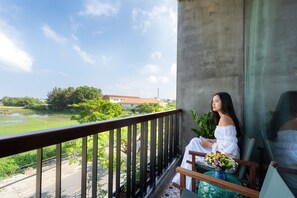 A balcony with a view of a green landscape and a building in the distance. - Paddy Boutique House Hoian (Da Nang)