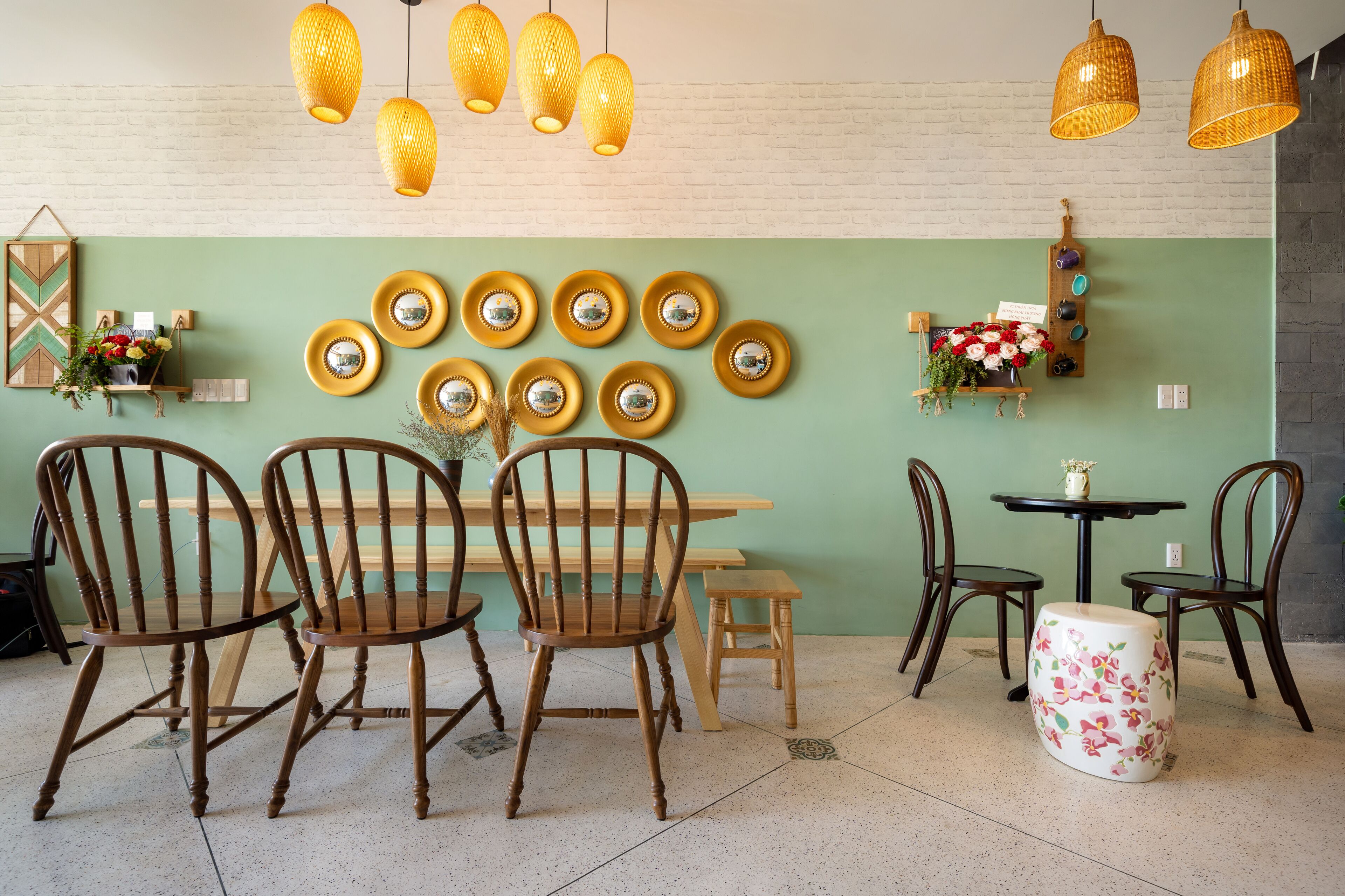 A dining area with wooden chairs, a table, and hanging yellow lamps.