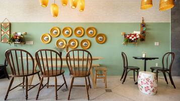 A dining area with wooden chairs, a table, and hanging yellow lamps.