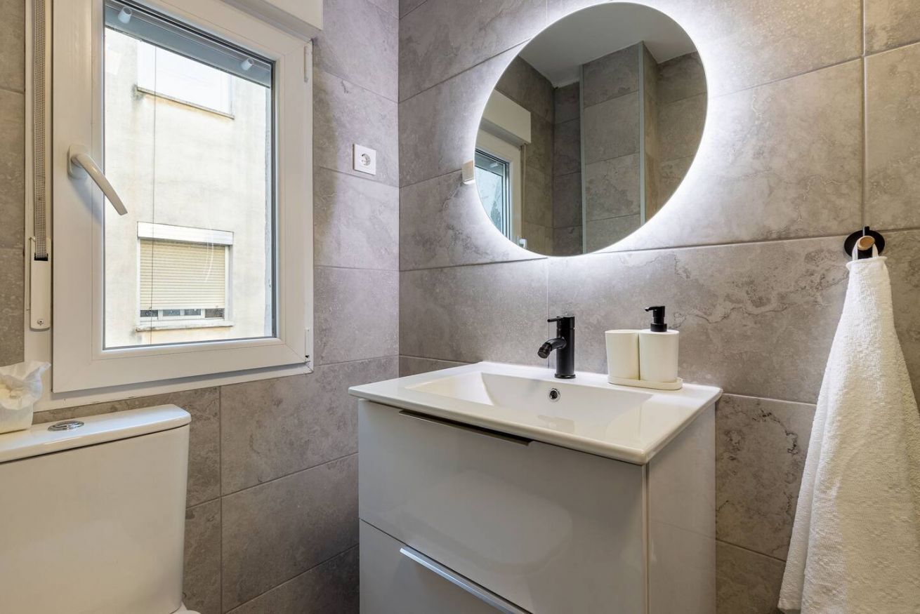 A bathroom with a white sink, a mirror, and a towel rack.