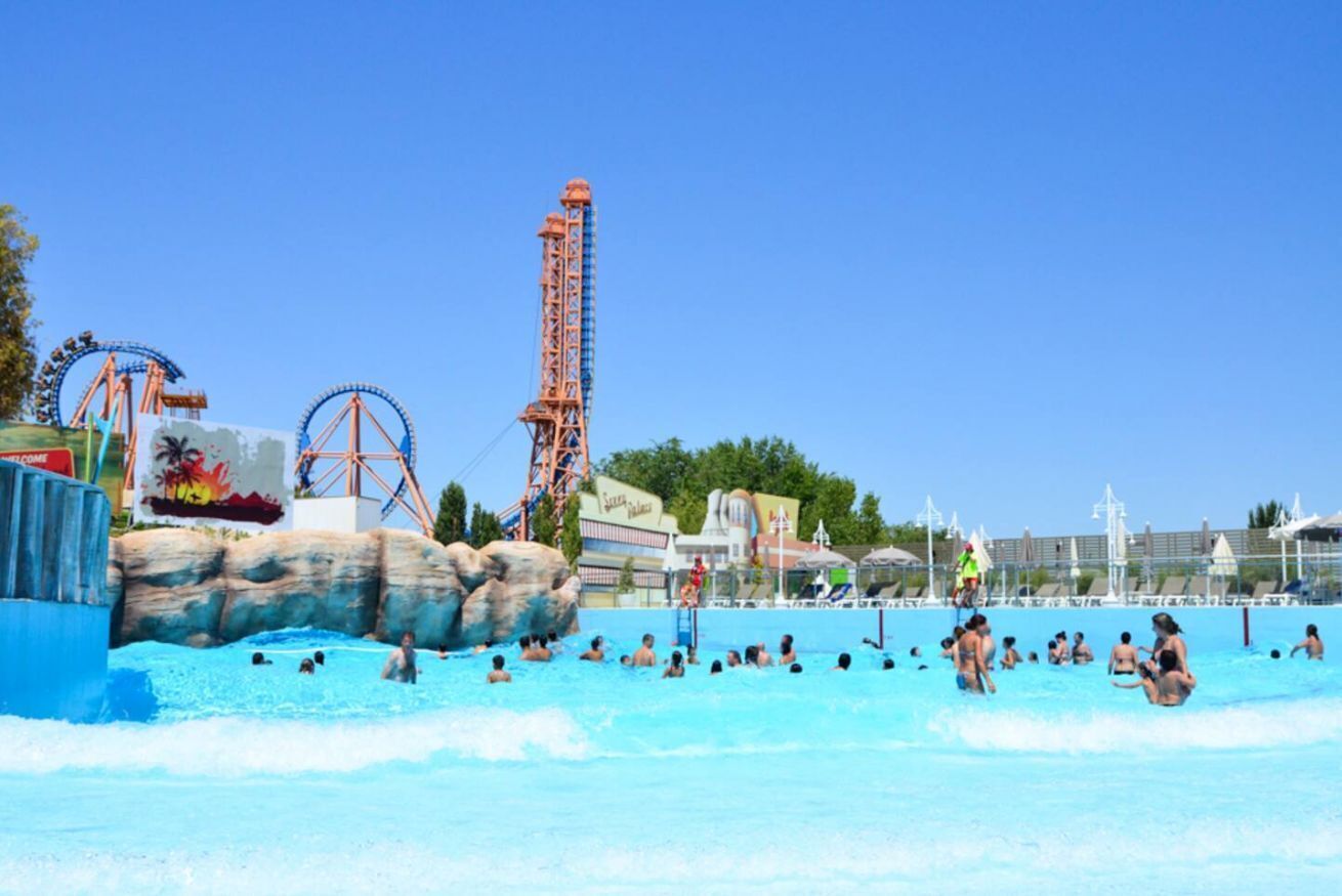 Un parque acuático con una piscina grande, una montaña rusa alta y una noria.