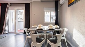 Un coin repas avec une table dressée pour quatre personnes, des chaises et une vue sur l’extérieur.