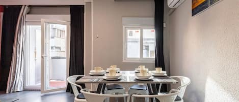 A dining area with a table set for four, chairs, and a view of the outside.